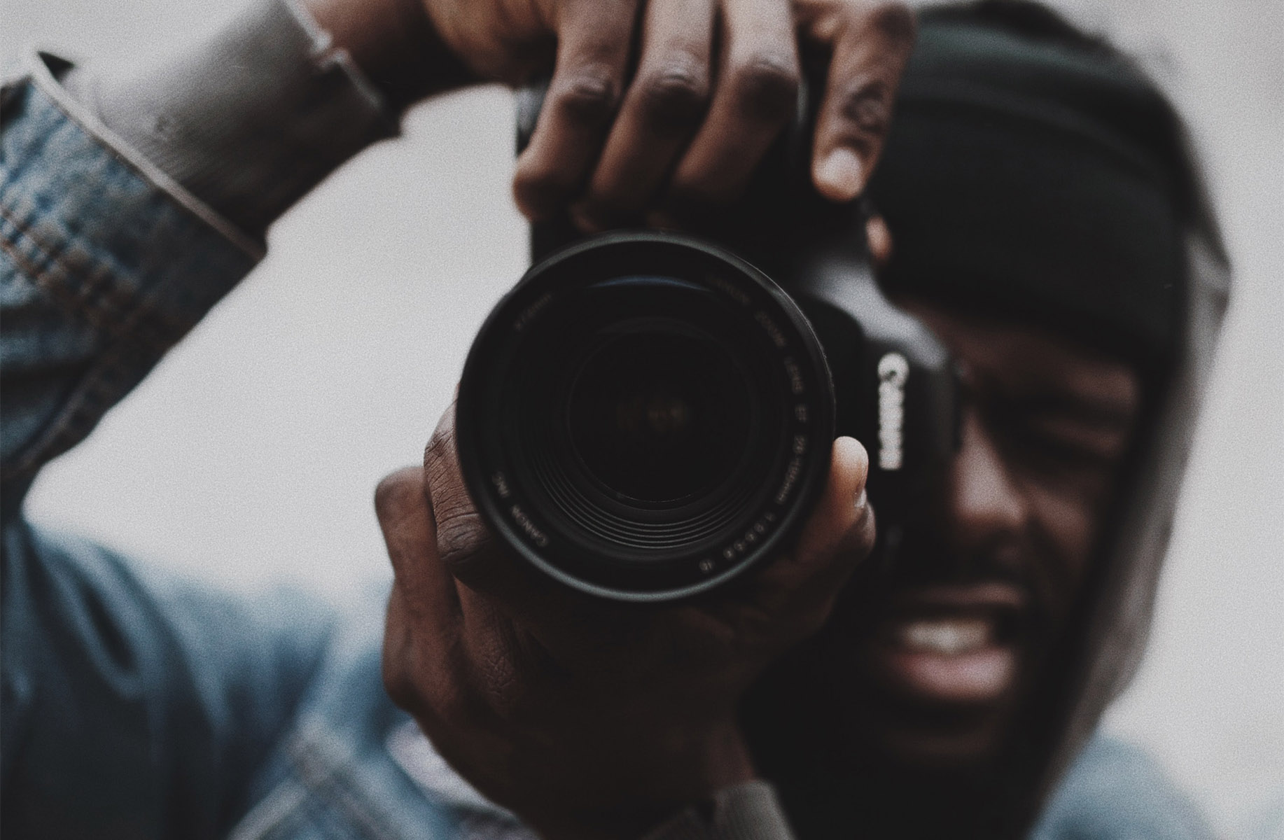 Person holding DSLR camera to their eye.