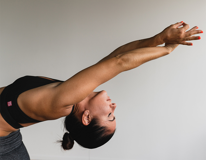 Person in sports bra bending backwards in yoga pose.
