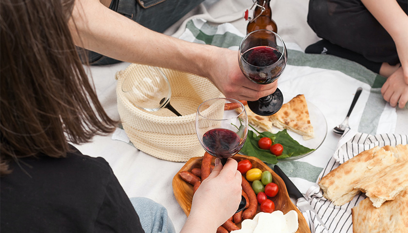Friends having an outdoor picnic with wine and food.